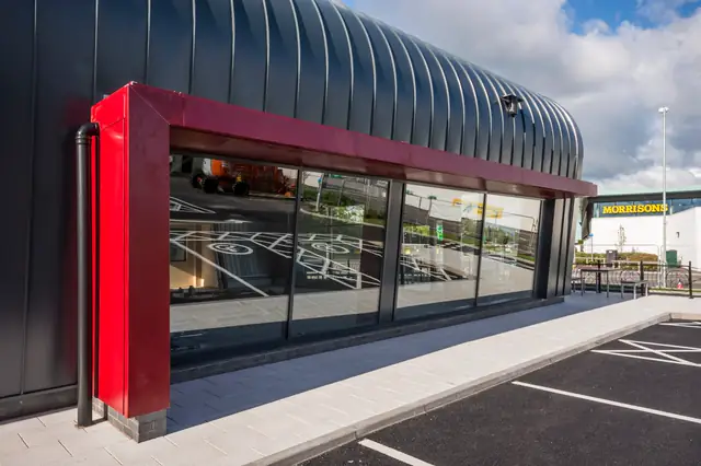 Glazed retail frontage with a crimson framed column beside the entrance